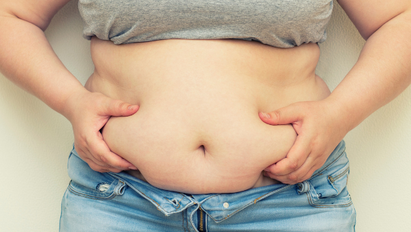 kobieta z otyłością brzuszną trzyma się za fałd skóry na brzuchu