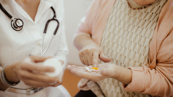 lekarz podaje kobiecie na dłoń tabletki na nietrzymanie moczu